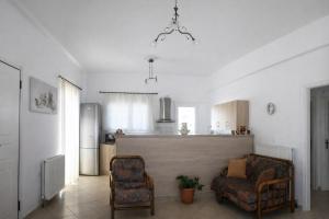 a living room with two chairs and a kitchen at Aegina House in Egina