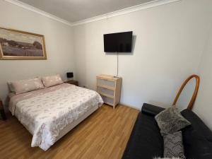 a bedroom with a bed and a tv on the wall at North Adelaide Studio in North Adelaide