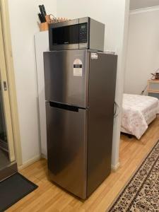 a stainless steel refrigerator with a microwave on top of it at North Adelaide Studio in North Adelaide