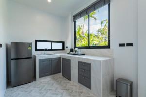 a kitchen with a sink and a refrigerator and a window at Nanuea Village Ao Nang in Ao Nang Beach