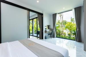 a bedroom with a large bed with a desk and large windows at Nanuea Village Ao Nang in Ao Nang Beach +53 photos