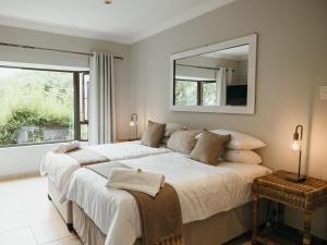 a bedroom with a large white bed and a mirror at Idube Guest House in Winterton