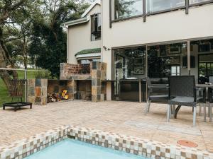 a patio with a fireplace next to a house at Idube Guest House in Winterton