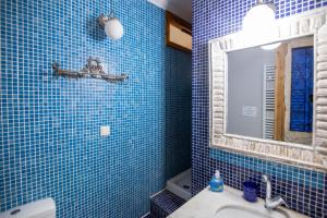 a blue tiled bathroom with a sink and a mirror at Blue Horizon Residence in Mitika +8 photos