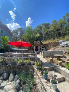 a patio with a red umbrella and some plants at Bilza A-House in Sagada