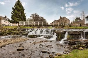 a waterfall in a town with houses and trees at Finest Retreats - Bourne Edge in Morland