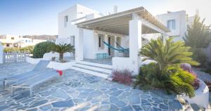 a white house with a bench and palm trees at Villa Ione in Mikri Vigla