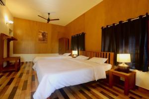 a bedroom with two white beds and two lamps at Coffee Courtyard - Boutique Estate Retreat, Coorg in Kurchi