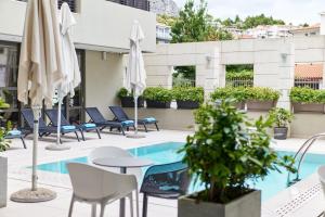 a hotel patio with chairs and umbrellas and a pool at Hotel Nestos in Omiš