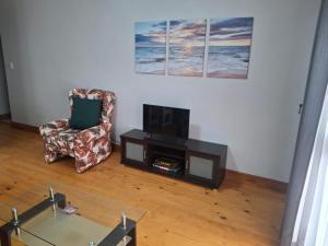 a living room with a chair and a television at R & A's Cottage in Strand