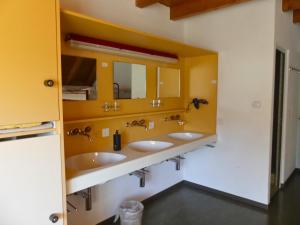 a bathroom with three sinks and a yellow wall at Gästehaus Gutenberg - Self-Check-in in Balzers +27 photos
