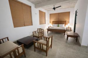 a bedroom with a bed and a couch and chairs at Stonewater Beach Villa, Negombo in Mahawatta