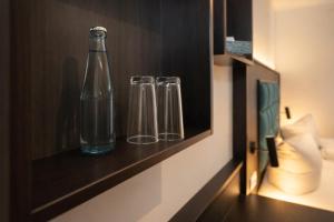 three glasses and a bottle on a shelf in a room at Hotel Hamburg Nord in Norderstedt +11 photos
