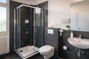 a bathroom with a shower and a toilet and a sink at Hotel Hamburg Nord in Norderstedt