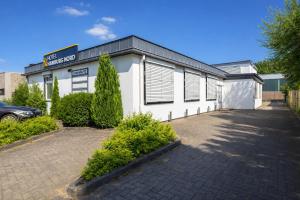 a white building with a parking lot in front of it at Hotel Hamburg Nord in Norderstedt