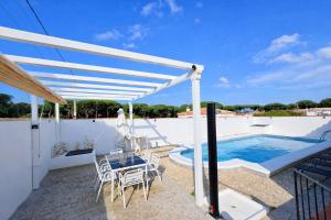 a white pergola over a patio with a swimming pool at Casa oasis de chiclana in Novo Sancti Petri