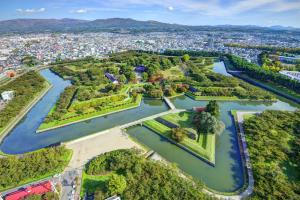 an aerial view of a park with a river and a city at HOTEL MYSTAYS Hakodate Station in Hakodate
