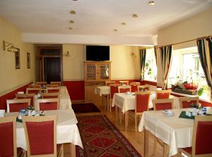 a restaurant with white tables and chairs and a television at Frühstückshotel Jammernegg in Köflach