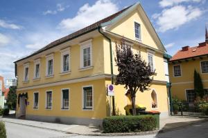 a yellow house with a tree in front of it at Frühstückshotel Jammernegg in Köflach
