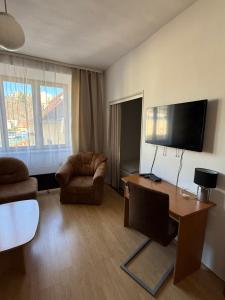 a living room with a desk and a tv at Penzion Vis a Vis in Třebíč