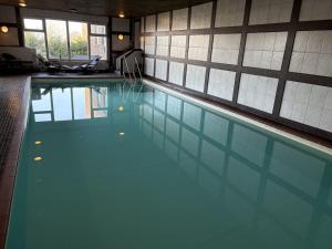 ein Schwimmbad mit blauem Wasser in einem Gebäude in der Unterkunft Hotel Wernerwald - Restaurant, Wellness & Events in Cuxhaven