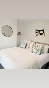 a white bedroom with two beds and a mirror at 171 Stroud Road in Gloucestershire