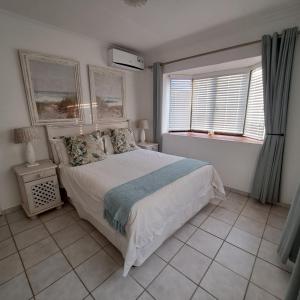 a bedroom with a large bed and two windows at Hibberdene Beachfront Self-Catering 9 Catalina Bay in Hibberdene