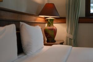 a bedroom with a bed with a lamp on a table at Erawan Phangnga Hotel, Natai Beach in Ban Na Phong