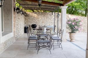 a table and chairs on a patio with a stone wall at La Bastide des Lavandins in Le Thor