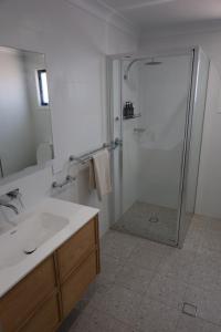 a bathroom with a shower and a sink and a mirror at Rivergums Cottage in Dubbo +17 photos