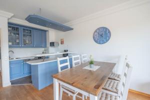 a kitchen with a wooden table and a clock on the wall at Küstenglück in Neustadt in Holstein +16 photos