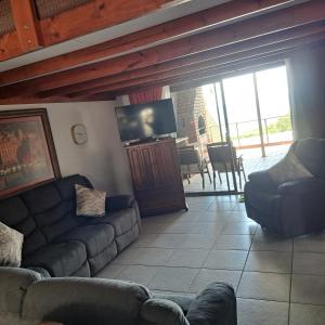 a living room with a couch and a flat screen tv at Hibberdene Beachfront Self-Catering 9 Catalina Bay in Hibberdene