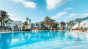 a large swimming pool with a slide in a resort at BLUESEA Corralejo Village in Corralejo