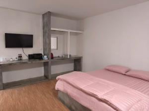 a bedroom with a bed and a flat screen tv at บ้านสวนร่มไม้แอ๊ดเชียงดาว in Ban Hua Thung