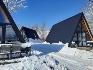 a building covered in snow with two chairs in front at Parc Sonnleiten - A Chalet in Gnesau