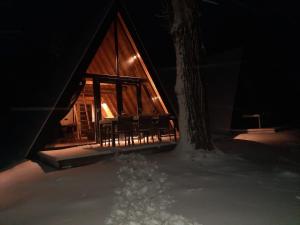 a cabin in the snow at night with a tree at Parc Sonnleiten - A Chalet in Gnesau +4 photos