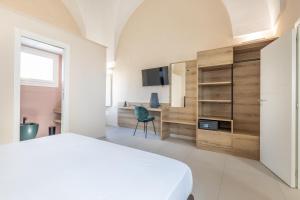 a bedroom with a bed and a desk and a television at Dimora Suite Platino in Gallipoli