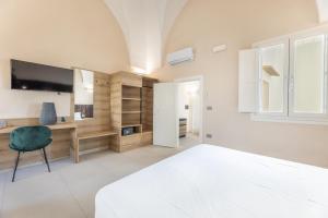 a bedroom with a bed and a desk and a television at Dimora Suite Platino in Gallipoli