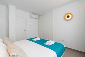 a white room with a bed and a orange clock on the wall at Ereza Suites in Arrecife