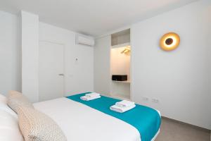 a white room with a bed with a blue blanket at Ereza Suites in Arrecife +33 photos