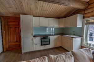a kitchen with white cabinets and a wooden ceiling at Meraftahornvegen 36 in Stranda +7 photos