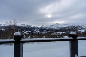 a fence with snow covered mountains in the background at Meraftahornvegen 36 in Stranda