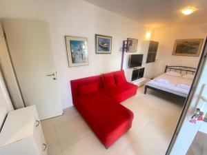 a red couch in a living room with a bed at Apartment Sanja in Primošten