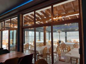 a dining room with tables and chairs and windows at Kompleks Koral Konak in Prezhda