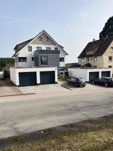 a white house with two cars parked in front of it at FeWo Müller in Simmersfeld +13 photos