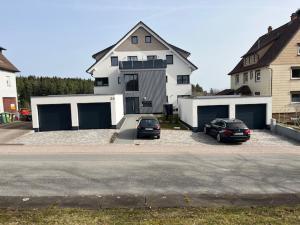 two cars parked in front of a large white house at FeWo Müller in Simmersfeld