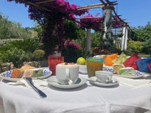 a table with cups and plates of food on it at Hotel Al Mulino - Mediterranean Garden Retreat in AnaCapri in Anacapri