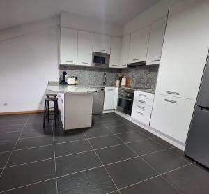a kitchen with white cabinets and a tile floor at Aldea Bricia 20 BC in Posada de Llanes