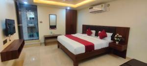 a bedroom with a bed with red pillows and a television at Hotel Manoj in Bhopal