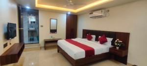 a bedroom with a bed with red pillows and a television at Hotel Manoj in Bhopal